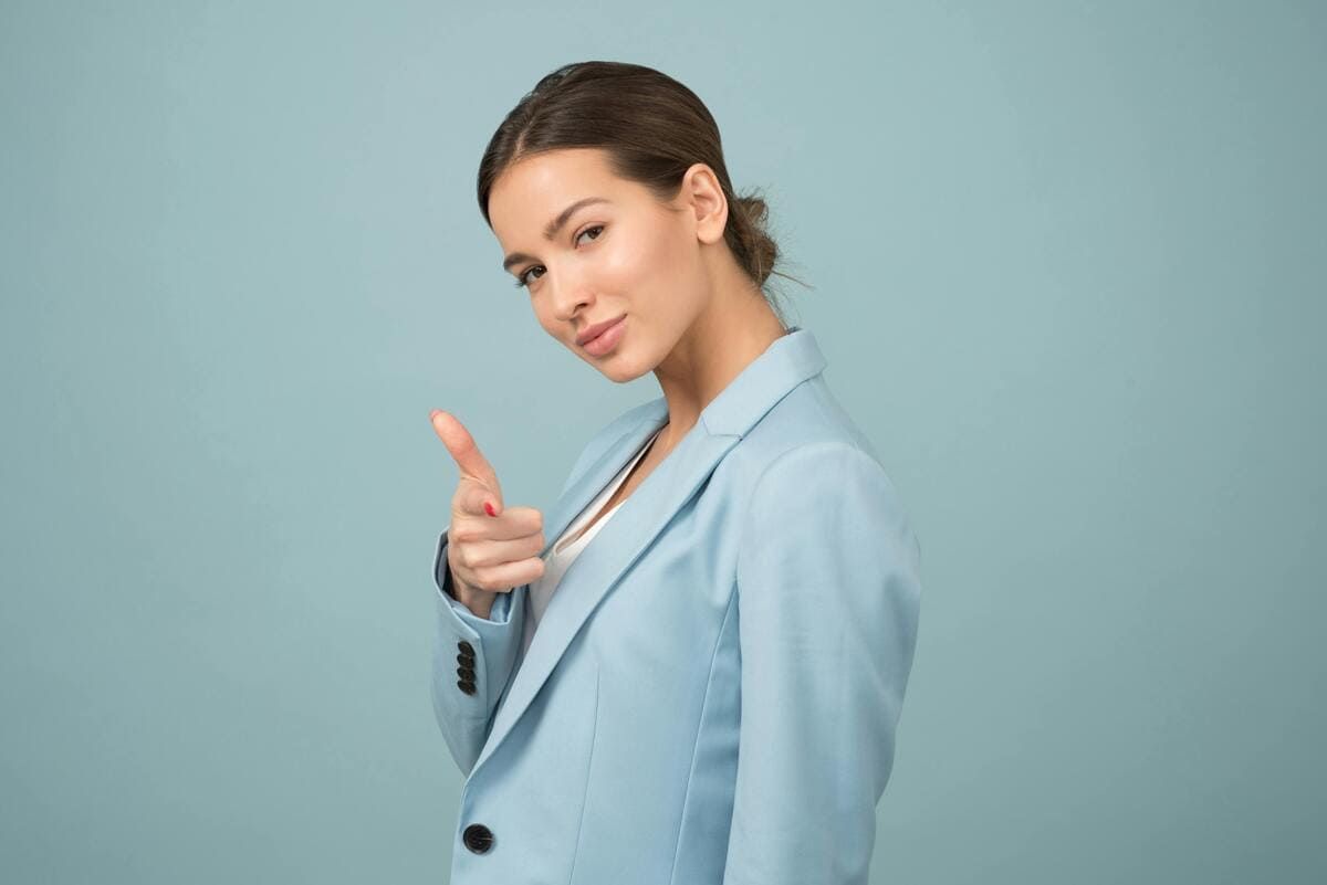 Une femme portant une veste bleu clair vous regarde en souriant