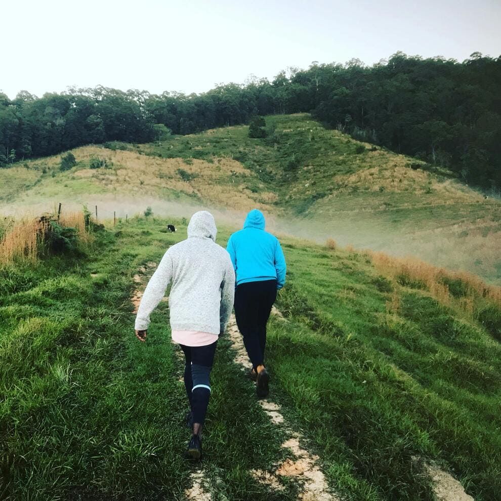 Deux personnes se promenent avec leur chien dans un pré